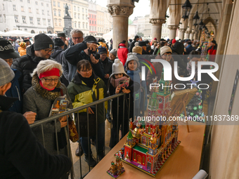 KRAKOW, POLAND - DECEMBER 05:
Visitors, tourists, and locals gather in Krakow's Main Square, capturing photos of the detailed handcrafted Na...