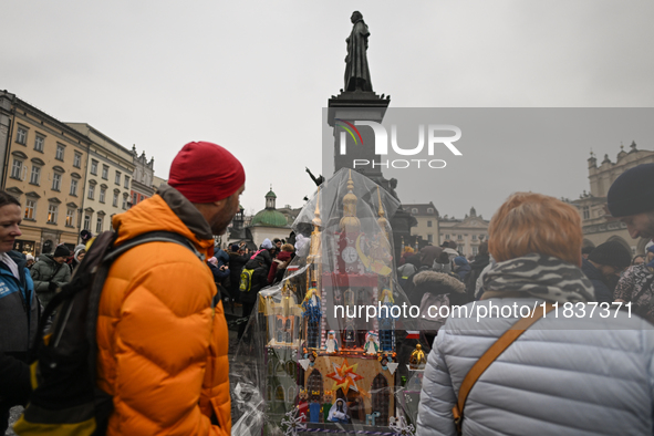 KRAKOW, POLAND - DECEMBER 05:
Visitors, tourists, and locals gather in Krakow's Main Square, capturing photos of the detailed handcrafted Na...