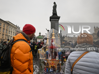 KRAKOW, POLAND - DECEMBER 05:
Visitors, tourists, and locals gather in Krakow's Main Square, capturing photos of the detailed handcrafted Na...