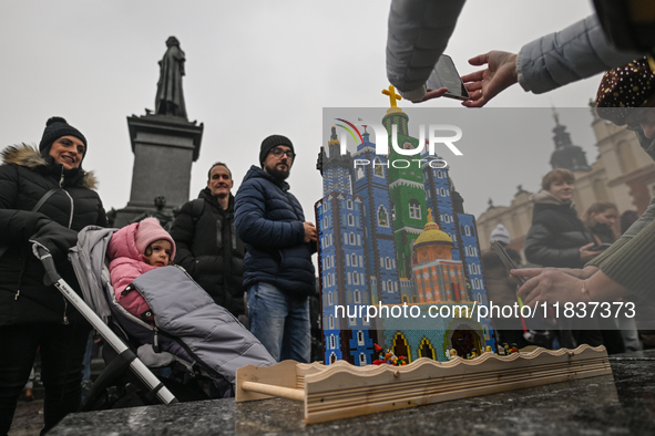 KRAKOW, POLAND - DECEMBER 05:
Visitors, tourists, and locals gather in Krakow's Main Square, capturing photos of the detailed handcrafted Na...