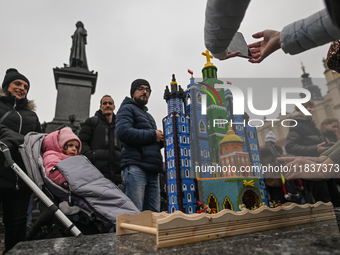 KRAKOW, POLAND - DECEMBER 05:
Visitors, tourists, and locals gather in Krakow's Main Square, capturing photos of the detailed handcrafted Na...