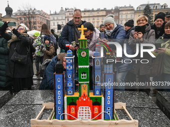 KRAKOW, POLAND - DECEMBER 05:
Visitors, tourists, and locals gather in Krakow's Main Square, capturing photos of the detailed handcrafted Na...