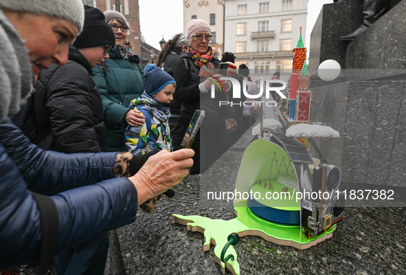 KRAKOW, POLAND - DECEMBER 05:
Visitors, tourists, and locals gather in Krakow's Main Square, capturing photos of the detailed handcrafted Na...