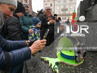 KRAKOW, POLAND - DECEMBER 05:
Visitors, tourists, and locals gather in Krakow's Main Square, capturing photos of the detailed handcrafted Na...