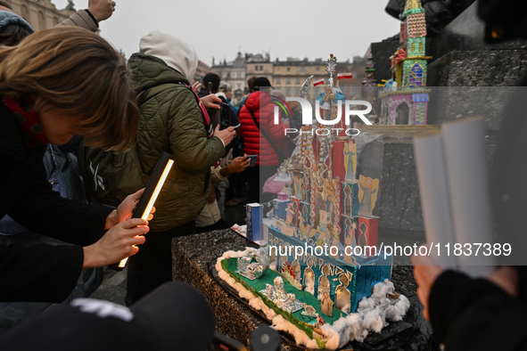 KRAKOW, POLAND - DECEMBER 05:
Visitors, tourists, and locals gather in Krakow's Main Square, capturing photos of the detailed handcrafted Na...