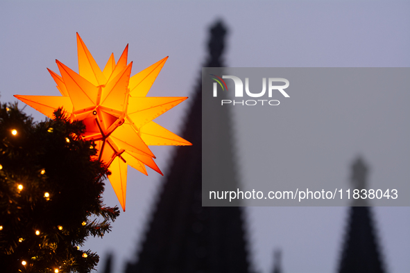 A general view of a Christmas star light is installed against the Dom Cathedral at the Cologne Christmas Market in Cologne, Germany, on Dece...