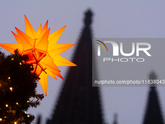 A general view of a Christmas star light is installed against the Dom Cathedral at the Cologne Christmas Market in Cologne, Germany, on Dece...