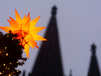 A general view of a Christmas star light is installed against the Dom Cathedral at the Cologne Christmas Market in Cologne, Germany, on Dece...