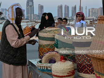 An Arab fisherman stacks baskets and mats made of palm leaves during the 14th Katara Traditional Dhow Festival in Katara Cultural Village in...