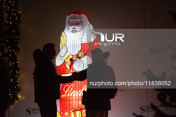 A general view shows tourists standing in front of an illuminated Lindt Santa Claus figure in front of the Lindt Chocolate Museum at the Col...