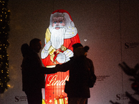 A general view shows tourists standing in front of an illuminated Lindt Santa Claus figure in front of the Lindt Chocolate Museum at the Col...