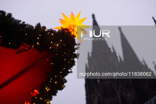 A general view of a Christmas star light is installed against the Dom Cathedral at the Cologne Christmas Market in Cologne, Germany, on Dece...