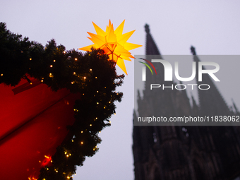 A general view of a Christmas star light is installed against the Dom Cathedral at the Cologne Christmas Market in Cologne, Germany, on Dece...