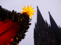 A general view of a Christmas star light is installed against the Dom Cathedral at the Cologne Christmas Market in Cologne, Germany, on Dece...