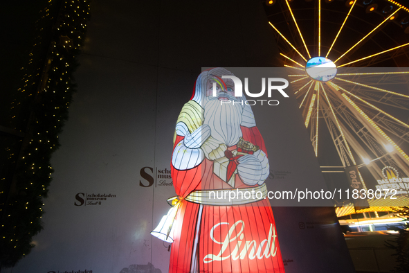 A general view shows an illuminated Lindt Santa Claus figure in front of the Lindt Chocolate Museum at the Cologne Harbor Christmas Market i...