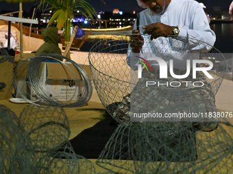 A man makes handicrafts during the 14th Katara Traditional Dhow Festival in Katara Cultural Village in Doha, Qatar, on December 5, 2024. The...