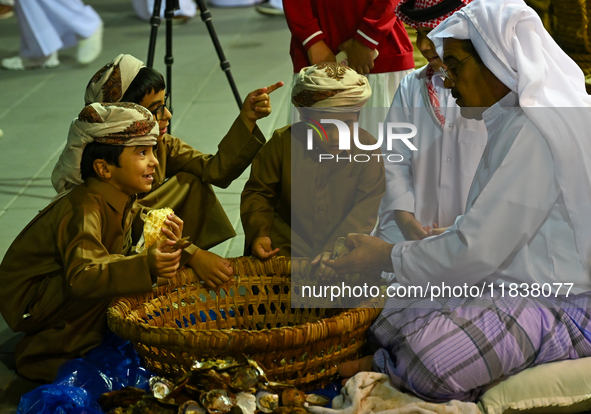 A Qatari man opens an oyster and extracts pearls during the 14th Katara Traditional Dhow Festival in Katara Cultural Village in Doha, Qatar,...