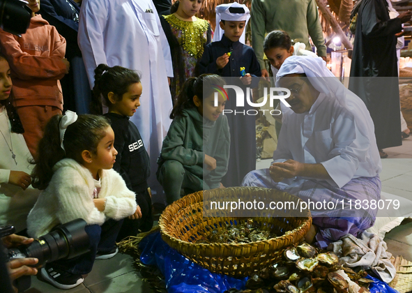 A Qatari man opens an oyster and extracts pearls during the 14th Katara Traditional Dhow Festival in Katara Cultural Village in Doha, Qatar,...