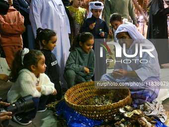 A Qatari man opens an oyster and extracts pearls during the 14th Katara Traditional Dhow Festival in Katara Cultural Village in Doha, Qatar,...