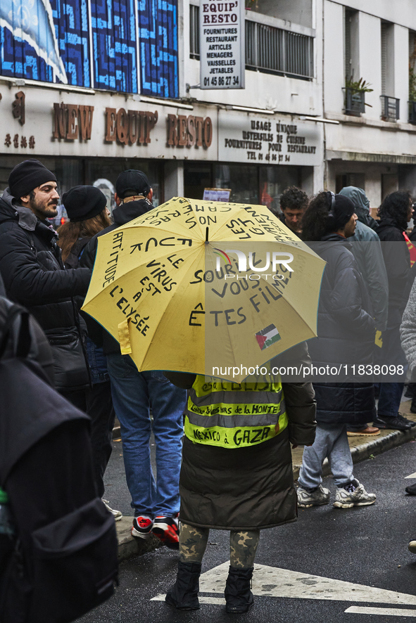 A protester holds an umbrella with slogans, in Paris, France, on december 05, 2024. ( Tony Linke/NurPhoto)