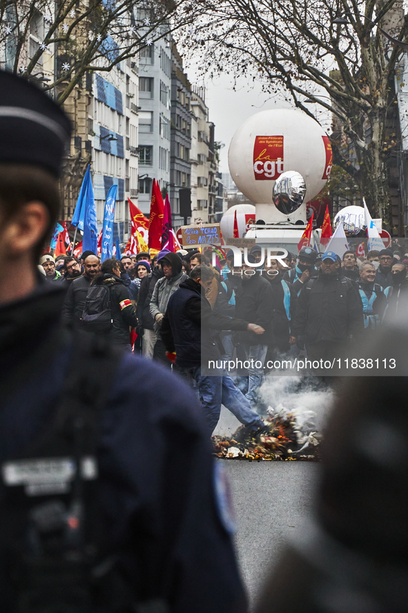 A man kicks the burning trash, in Paris, France, on december 05, 2024. ( Tony Linke/NurPhoto)