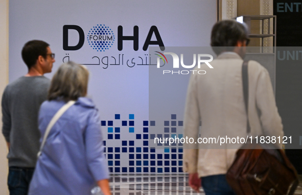 People walk past the Doha Forum logo inside the Sheraton Grand Doha Resort & Convention Hotel ahead of the 22nd edition of the Doha Forum in...