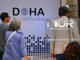 People walk past the Doha Forum logo inside the Sheraton Grand Doha Resort & Convention Hotel ahead of the 22nd edition of the Doha Forum in...