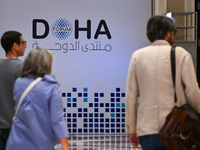 People walk past the Doha Forum logo inside the Sheraton Grand Doha Resort & Convention Hotel ahead of the 22nd edition of the Doha Forum in...