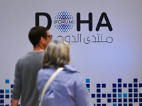 People walk past the Doha Forum logo inside the Sheraton Grand Doha Resort & Convention Hotel ahead of the 22nd edition of the Doha Forum in...