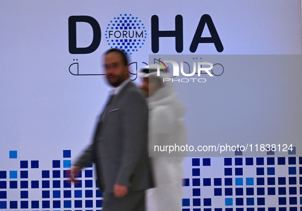 People walk past the Doha Forum logo inside the Sheraton Grand Doha Resort & Convention Hotel ahead of the 22nd edition of the Doha Forum in...