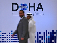 People walk past the Doha Forum logo inside the Sheraton Grand Doha Resort & Convention Hotel ahead of the 22nd edition of the Doha Forum in...