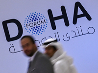 People walk past the Doha Forum logo inside the Sheraton Grand Doha Resort & Convention Hotel ahead of the 22nd edition of the Doha Forum in...