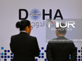 People walk past the Doha Forum logo inside the Sheraton Grand Doha Resort & Convention Hotel ahead of the 22nd edition of the Doha Forum in...