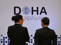 People walk past the Doha Forum logo inside the Sheraton Grand Doha Resort & Convention Hotel ahead of the 22nd edition of the Doha Forum in...