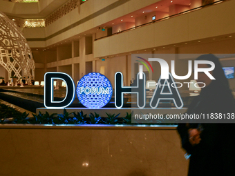 A woman walks past the Doha Forum logo inside the Sheraton Grand Doha Resort & Convention Hotel ahead of the 22nd edition of the Doha Forum...