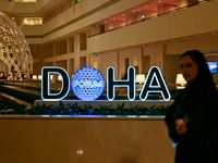 A woman walks past the Doha Forum logo inside the Sheraton Grand Doha Resort & Convention Hotel ahead of the 22nd edition of the Doha Forum...