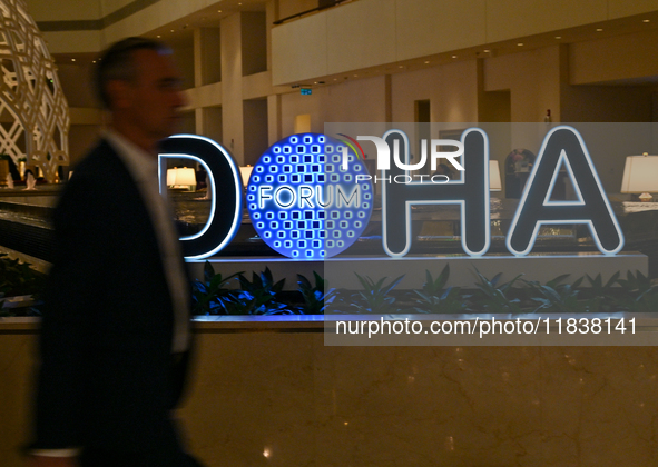 A man walks past the Doha Forum logo inside the Sheraton Grand Doha Resort & Convention Hotel ahead of the 22nd edition of the Doha Forum in...