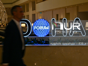 A man walks past the Doha Forum logo inside the Sheraton Grand Doha Resort & Convention Hotel ahead of the 22nd edition of the Doha Forum in...