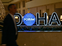 A man walks past the Doha Forum logo inside the Sheraton Grand Doha Resort & Convention Hotel ahead of the 22nd edition of the Doha Forum in...