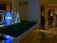 People walk past the Doha Forum logo inside the Sheraton Grand Doha Resort & Convention Hotel ahead of the 22nd edition of the Doha Forum in...