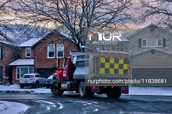 A snow plow applies ice-melting road salt to a road following the first snowfall of the season in Toronto, Ontario, Canada, on December 5, 2...