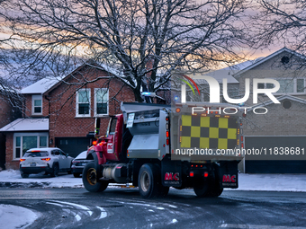 A snow plow applies ice-melting road salt to a road following the first snowfall of the season in Toronto, Ontario, Canada, on December 5, 2...