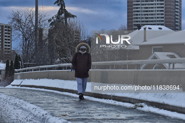 A woman walks along an icy sidewalk following the first snowfall of the season in Toronto, Ontario, Canada, on December 5, 2024. 