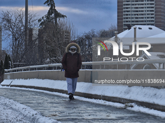 A woman walks along an icy sidewalk following the first snowfall of the season in Toronto, Ontario, Canada, on December 5, 2024. (