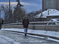 A woman walks along an icy sidewalk following the first snowfall of the season in Toronto, Ontario, Canada, on December 5, 2024. (