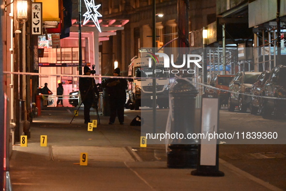 NYPD Crime Scene Unit investigators mark the crime scene where a 17-year-old boy is killed and an 18-year-old man is injured after they are...