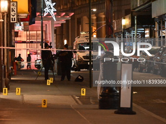 NYPD Crime Scene Unit investigators mark the crime scene where a 17-year-old boy is killed and an 18-year-old man is injured after they are...