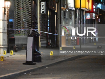 NYPD Crime Scene Unit investigators mark the crime scene where a 17-year-old boy is killed and an 18-year-old man is injured after they are...