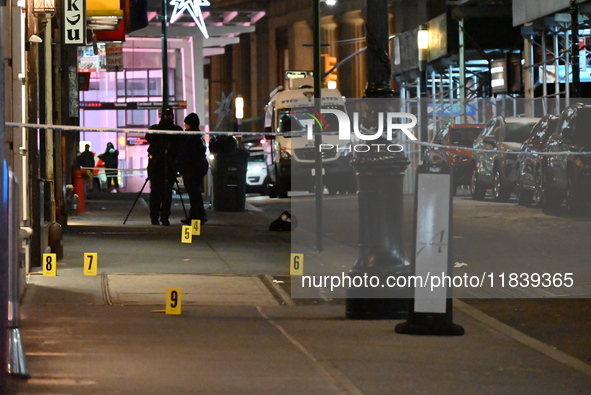 NYPD Crime Scene Unit investigators mark the crime scene where a 17-year-old boy is killed and an 18-year-old man is injured after they are...