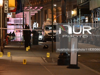 NYPD Crime Scene Unit investigators mark the crime scene where a 17-year-old boy is killed and an 18-year-old man is injured after they are...